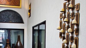 A hallway with a glass door, a wall-mounted light fixture, and large vases on a table. - Hotel Suites Sofia (Querétaro)