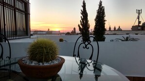 A rooftop terrace with a glass table, a potted cactus, and two tall trees. - Hotel Suites Sofia (Querétaro)
