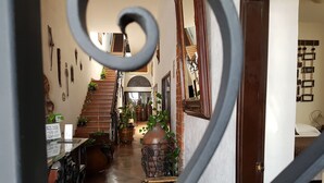 A hallway with a staircase, potted plants, and a mirror. - Hotel Suites Sofia (Querétaro)