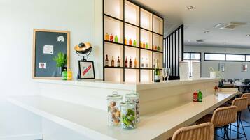 A modern bar area with shelves of beverages, a framed picture, and a potted plant.