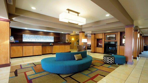 Un hall d’hôtel avec un canapé bleu, un tapis à motifs, un comptoir de réception et une cheminée.
