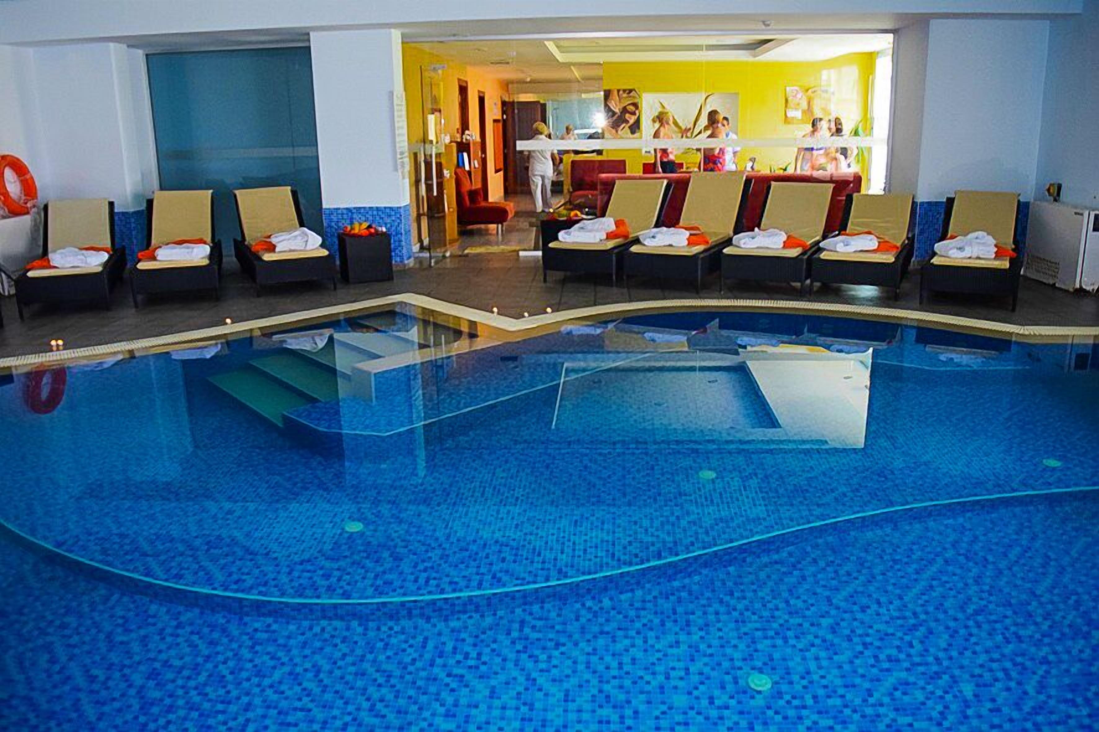 Una piscina con lettini e asciugamani, una zona reception e un bar.