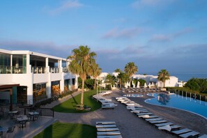 A resort with a pool, outdoor seating, and palm trees. - Theo Sunset Bay Hotel (Kissonerga)