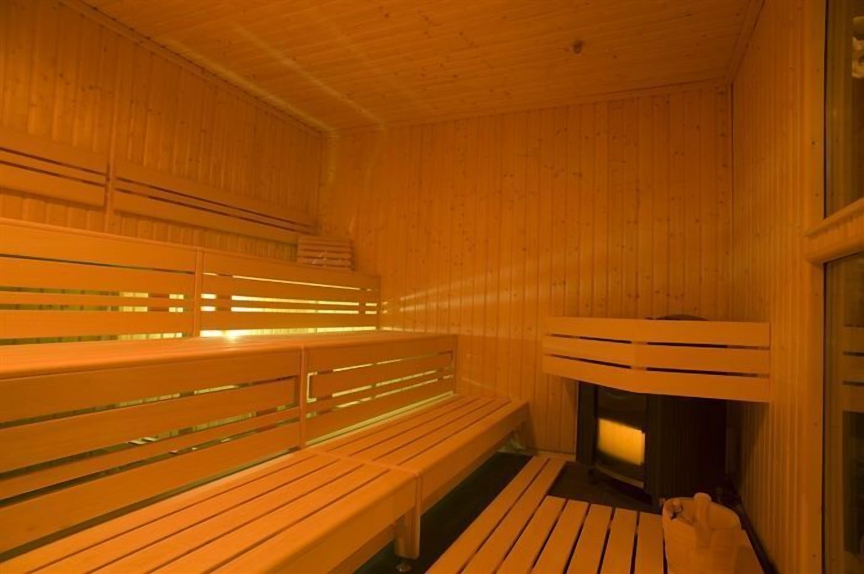 Una sauna de madera con bancos y un elemento calefactor visible.