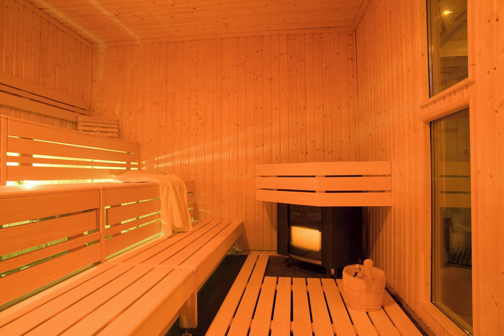 A sauna room with wooden benches and a stone fireplace.