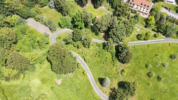 An aerial view of a campus with multiple buildings, winding roads, and surrounding greenery.