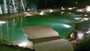 Une vue nocturne d’une piscine avec une terrasse en bois.