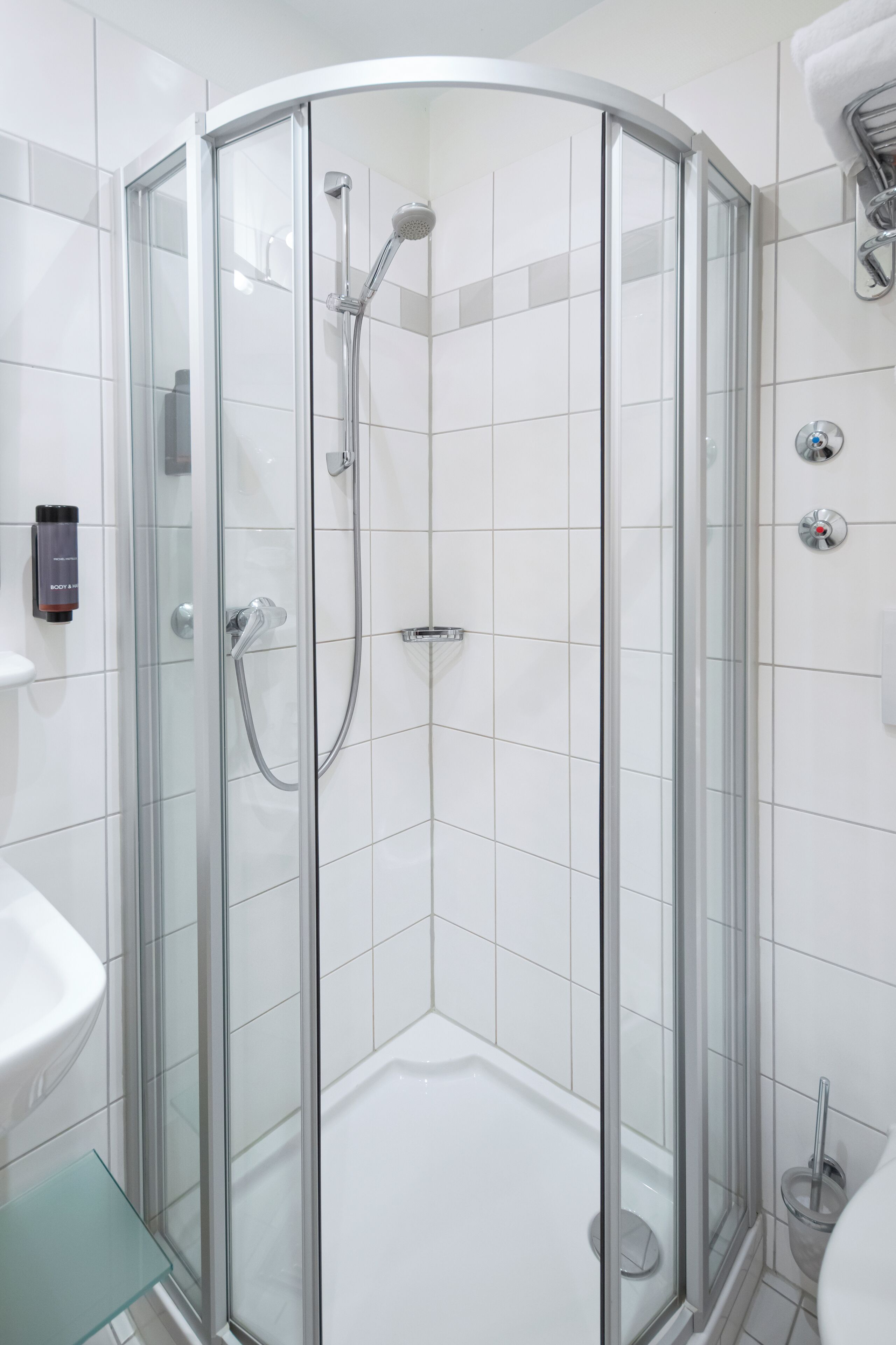 Ein modernes Badezimmer mit einer gläsernen Dusche, einem weißen Waschbecken und einem Glastregal.