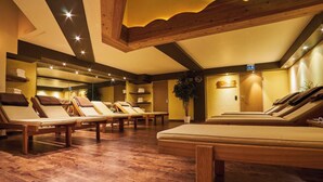 Une salle de spa dotée de planchers en bois, de plusieurs chaises longues et d’un grand lit.
