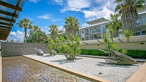 A pool area with palm trees, a pebble-lined walkway, and a modern building with balconies. - Peppers Salt Resort & Spa (Kingscliff)