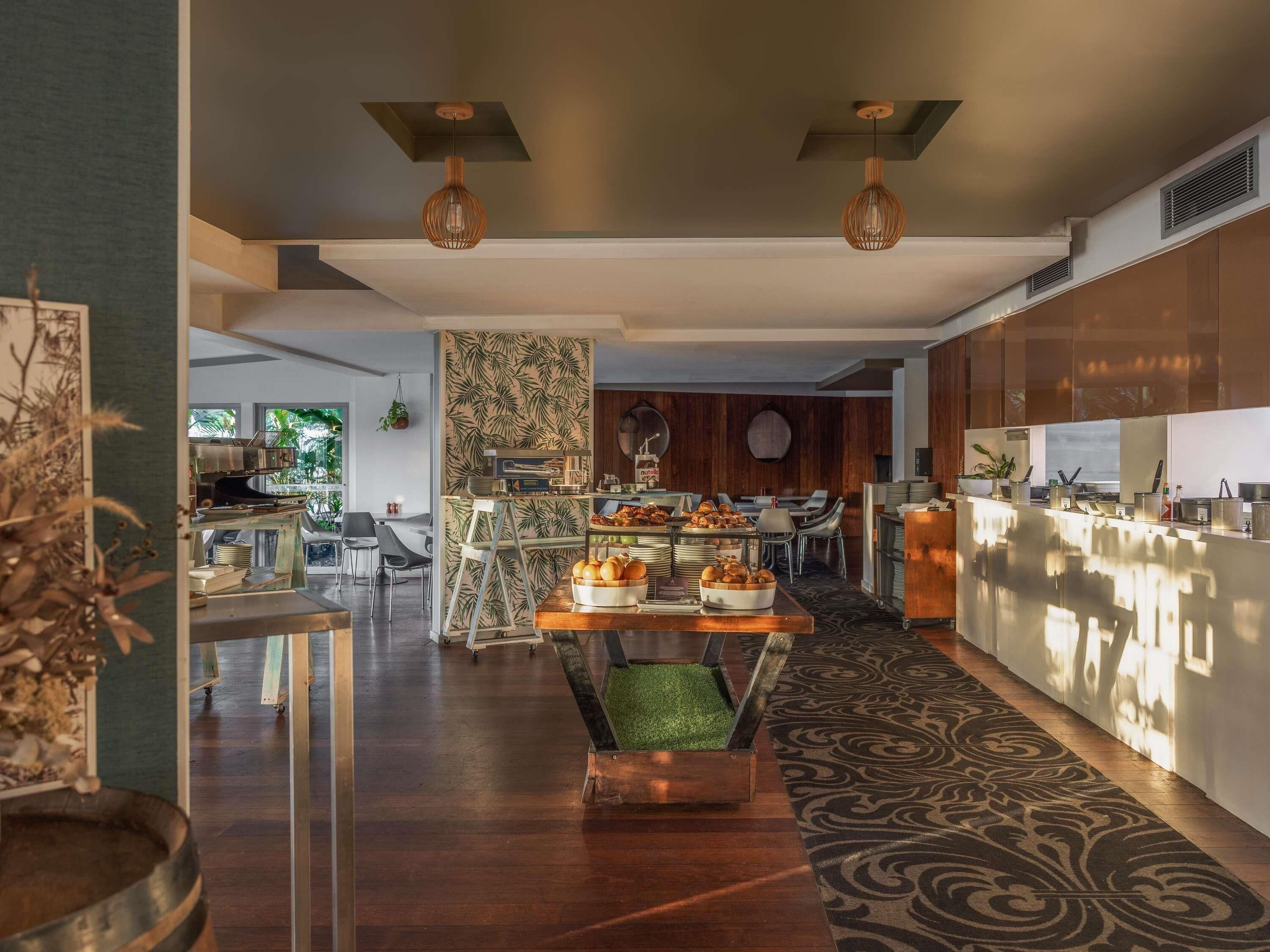 Un hall d’hôtel moderne doté d’un espace de restauration central, d’un coin café et d’un comptoir d’accueil.