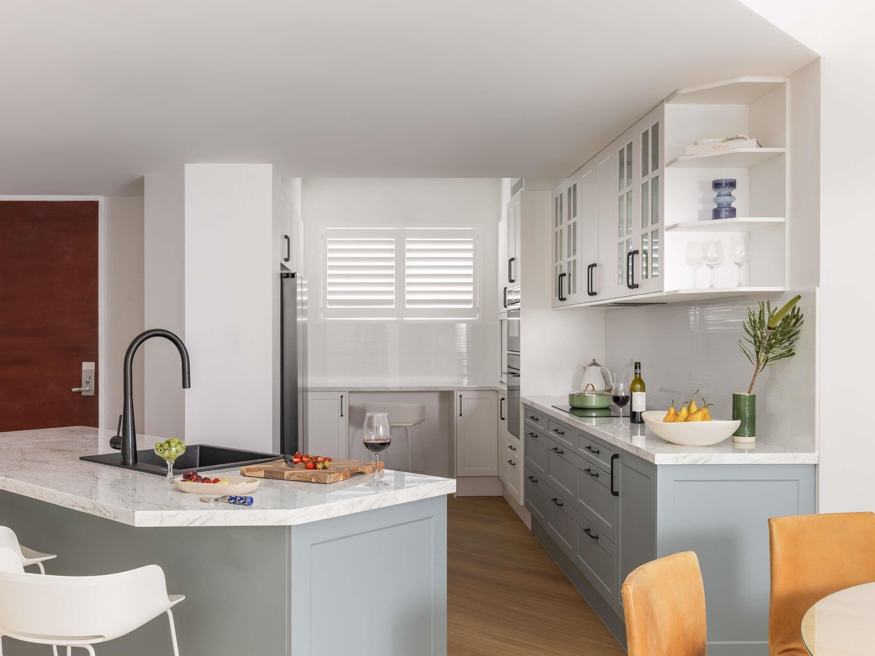 A modern kitchen with a central island, white cabinetry, and a built-in wine rack.