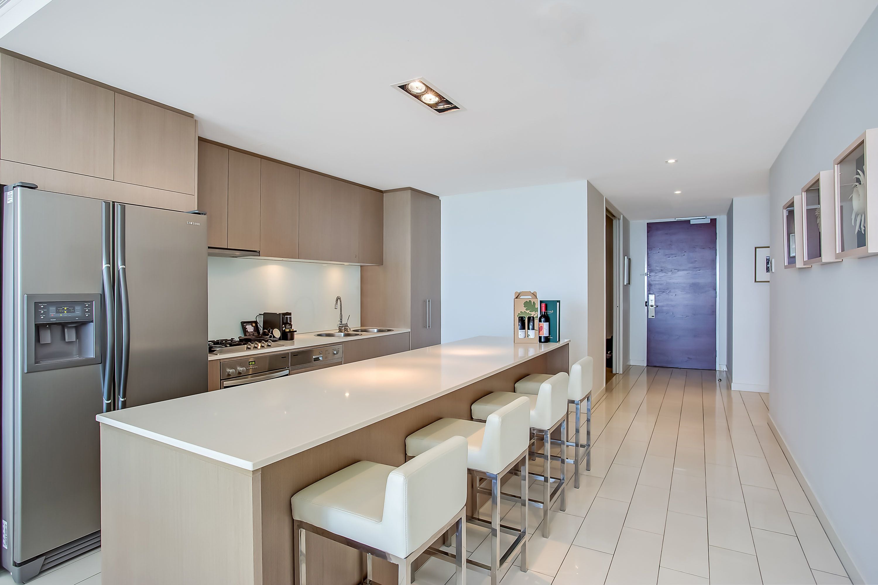 A modern kitchen with a central island, stainless steel appliances, and a long countertop.