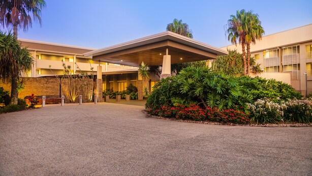 A hotel entrance with a covered walkway, palm trees, and a landscaped garden. - Peppers Salt Resort & Spa (Kingscliff)
