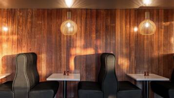 Un intérieur moderne avec des murs lambrés en bois, des fauteuils en cuir noir et des tables blanches.