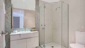 Une salle de bain moderne avec une douche à parois de verre, un lavabo blanc et des toilettes.