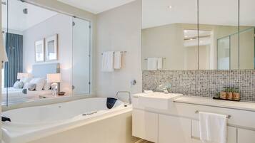A modern bathroom with a large bathtub, a vanity with a mirror, and a tiled backsplash.