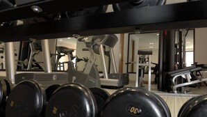 Ein Fitnessstudio mit verschiedenen Trainingsgeräten, darunter Hanteln, Laufbänder und Kraftmaschinen.