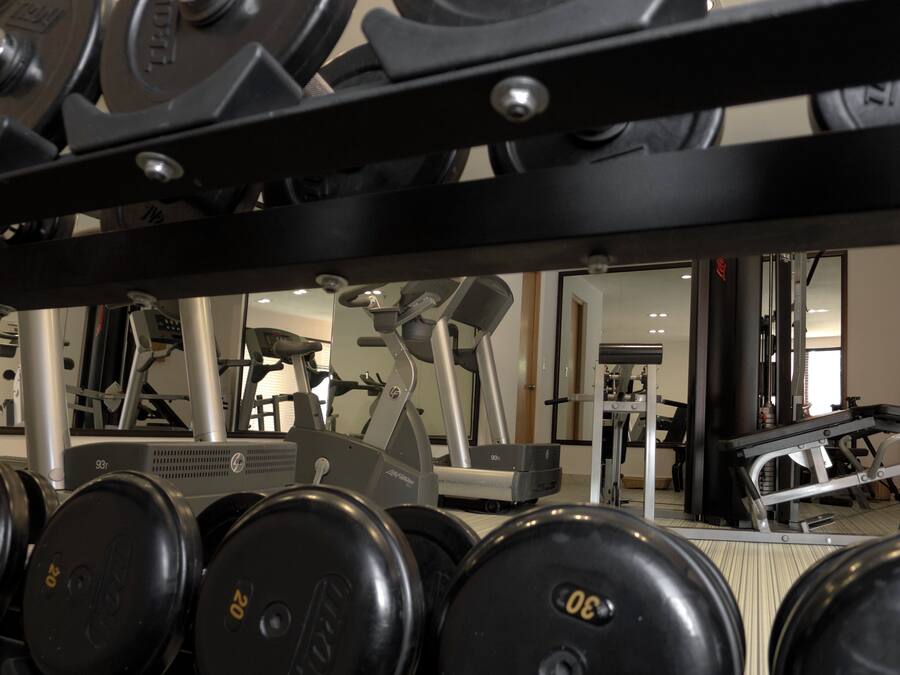Una palestra con diverse attrezzature per l'allenamento, tra cui manubri, tapis roulant e macchinari per pesi.