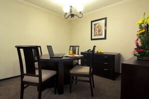 A small, private dining area with a round table, two chairs, a laptop, a phone, and a vase of flowers. - Fiesta Inn Toluca Centro (Toluca)