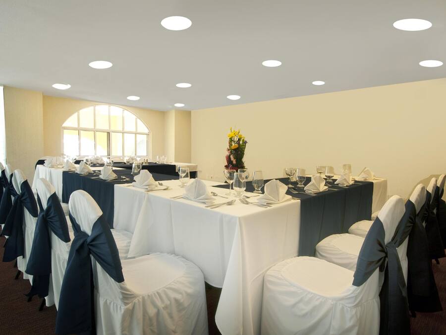 A conference room with round tables, white chairs with blue sashes, and a floral centerpiece.