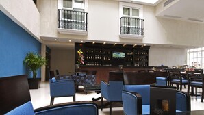 Eine Hotelhalle mit Barbereich, Sitzgelegenheiten und einem großen Fenster, das für natürliches Licht sorgt.