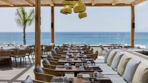 An outdoor restaurant with wooden tables and chairs, overlooking the sea. - Mitsis Norida (Kos)