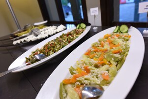 A buffet table with various dishes including salads and vegetables.