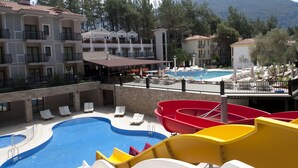 A resort with a swimming pool, lounge chairs, and a mountain backdrop. - Hotel Pine Valley (Fethiye)