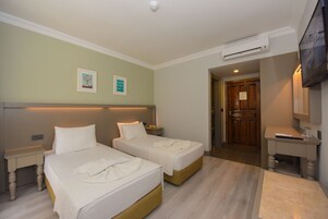 Een hotelkamer met twee bedden, een bureau, een televisietoestel en een airconditioning.