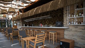 Un espace bar avec des meubles en bois et un plafond recouvert de chaume.