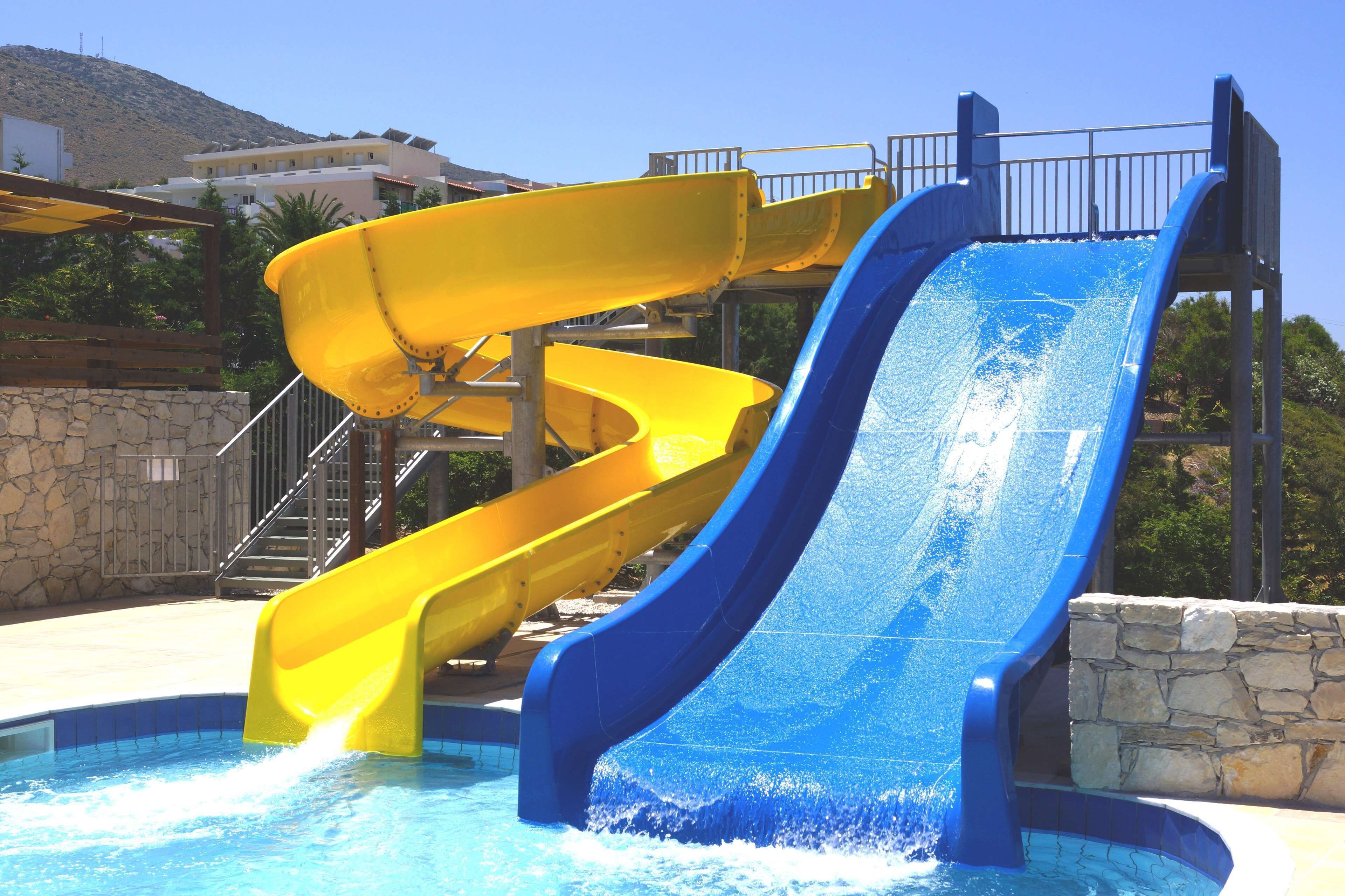 Un parc aquatique avec deux toboggans, un jaune et un bleu, et une zone avec des piscines.