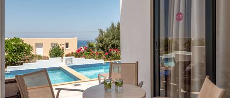 A balcony with a pool, chairs, and a table with drinks.
