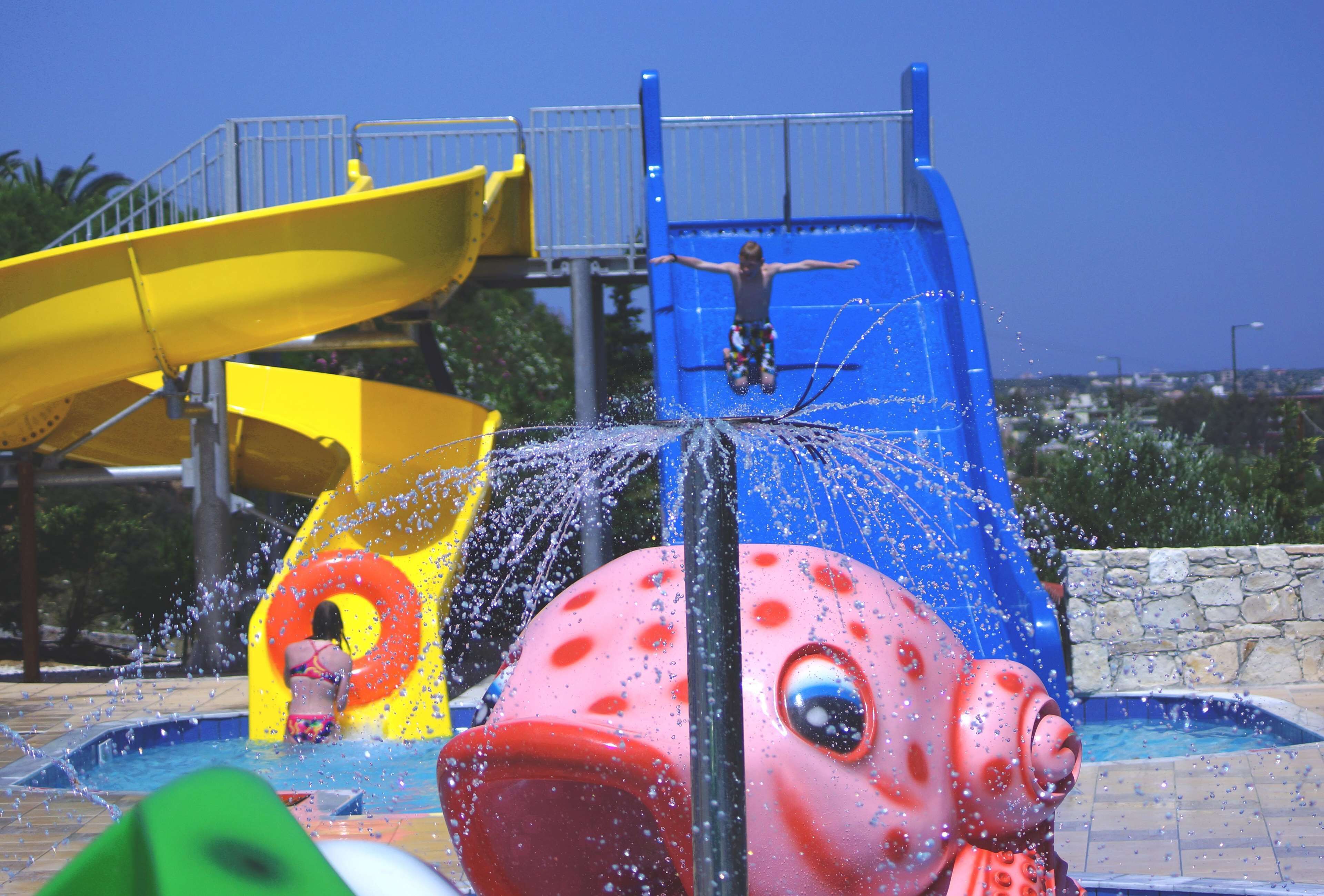 Een waterpark met een grote glijbaan, een fontein en een zwembad.