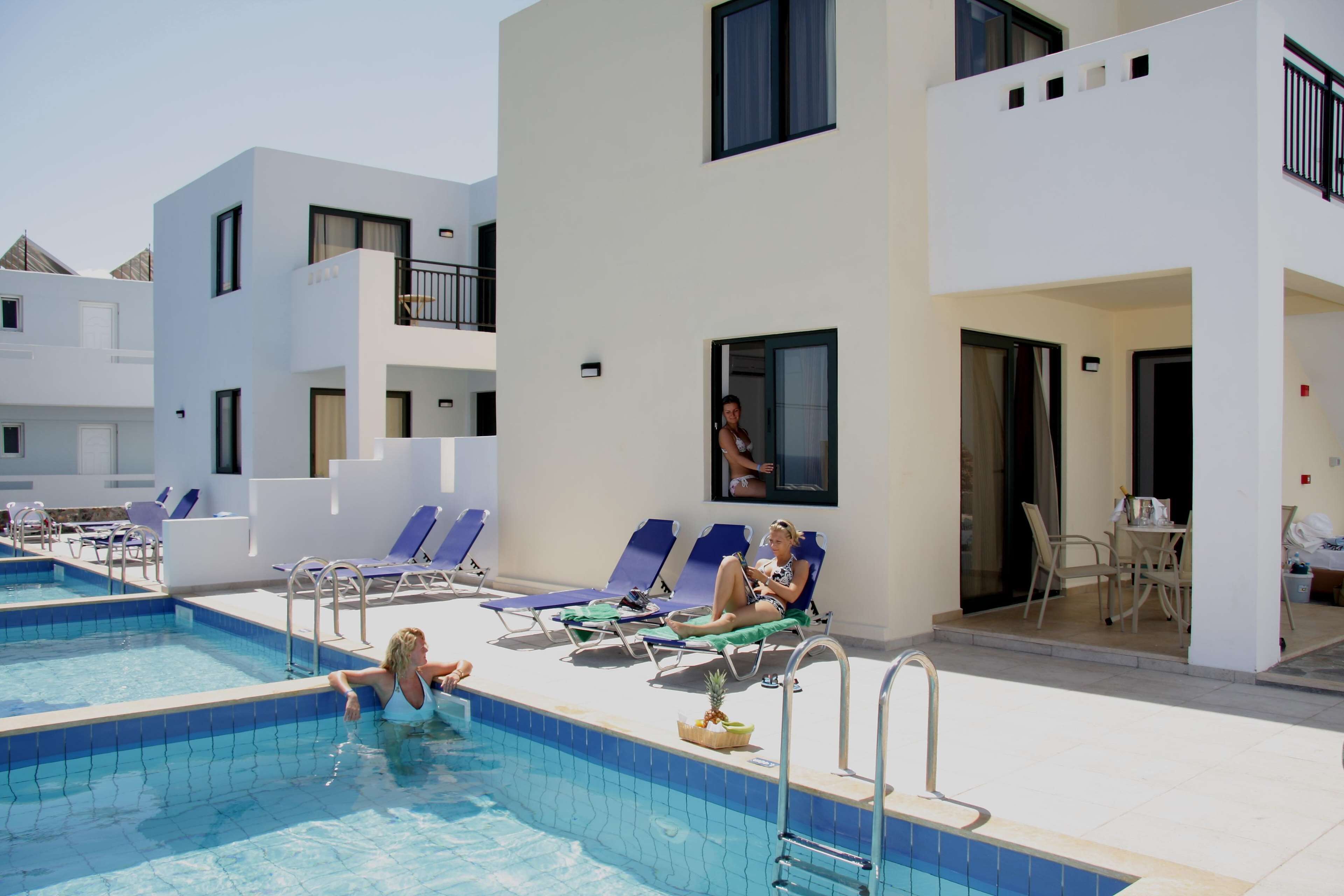 Zona de piscina con sillas de descanso y una persona nadando.