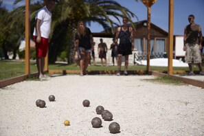 Un terrain de croquet avec des boules et des joueurs en arrière-plan.