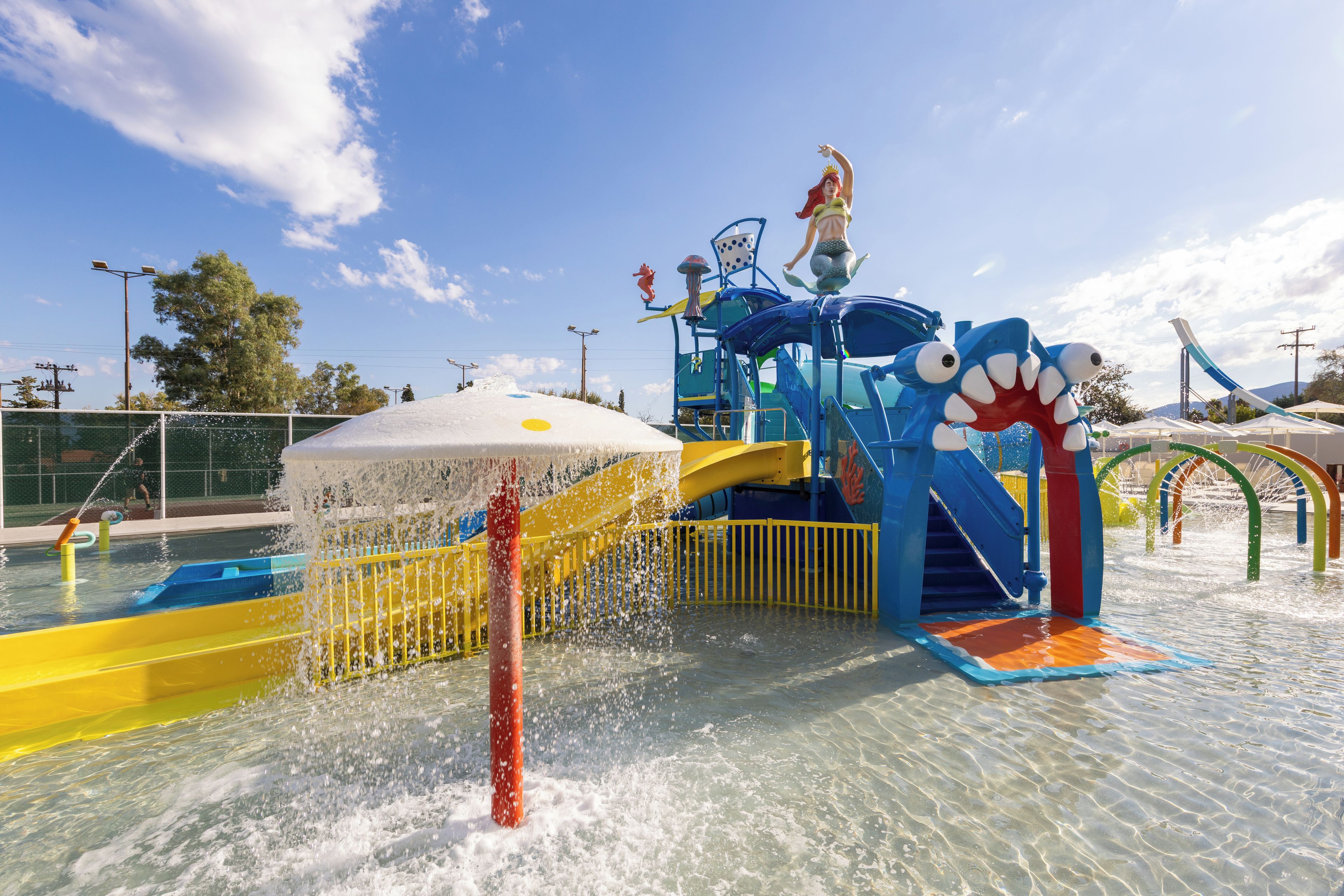 A water park with a water slide, a mermaid statue, and a shark play structure.