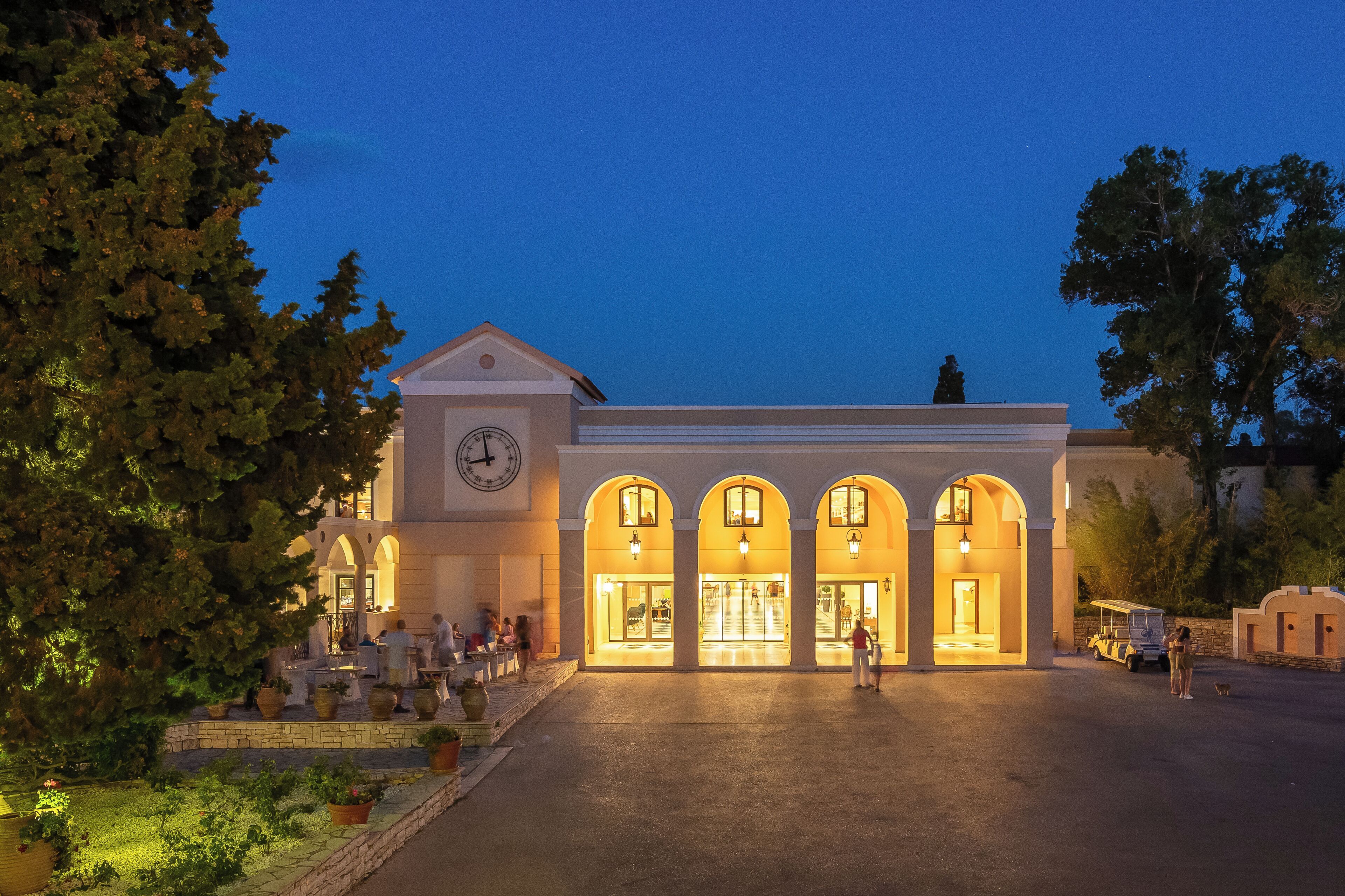 A hotel with a clock tower, arched entrance, and outdoor seating area.