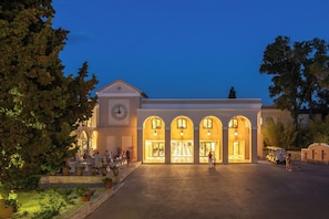 A hotel with a clock tower, arched entrance, and outdoor seating area.