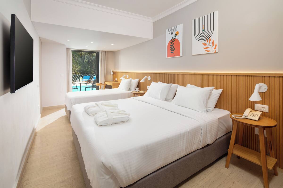 Una camera d'hotel con due letti, una televisione, un telefono e opere d'arte alle pareti.