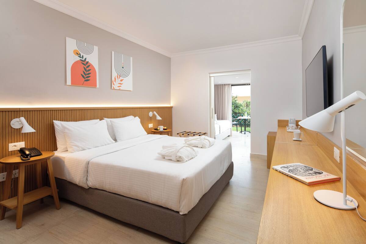 Una moderna camera d'albergo con un letto grande, comodini con lampade, una televisione a schermo piatto e opere d'arte alle pareti.