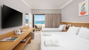A hotel room with two beds, a TV, a desk with a coffee maker, and a view of the beach. - Roda Beach Resort & Spa All-inclusive (Corfu)