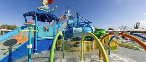 A water park with a water slide, splash pad, and a mermaid statue.