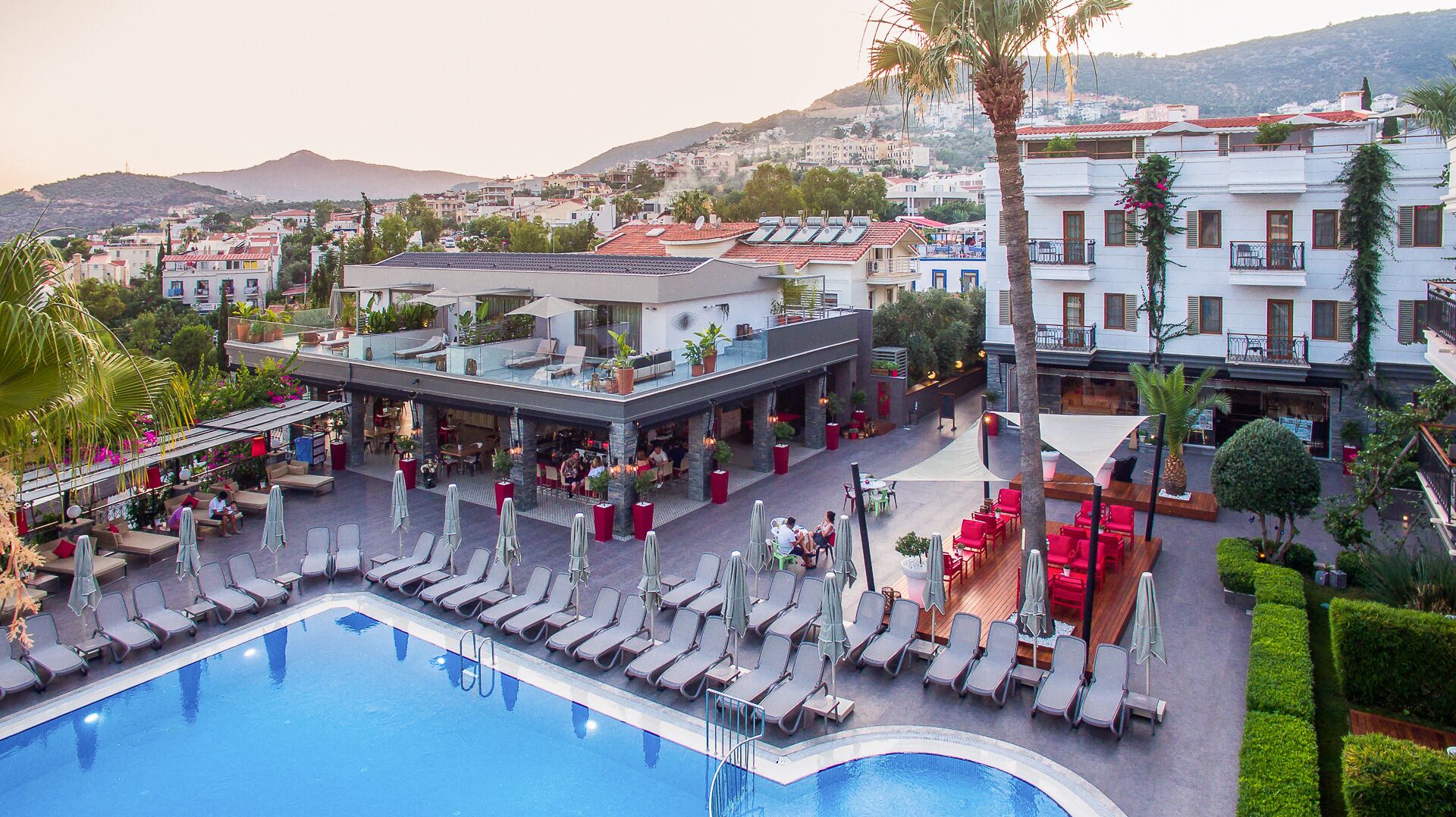 A hotel with a pool, outdoor seating, and a view of the city.