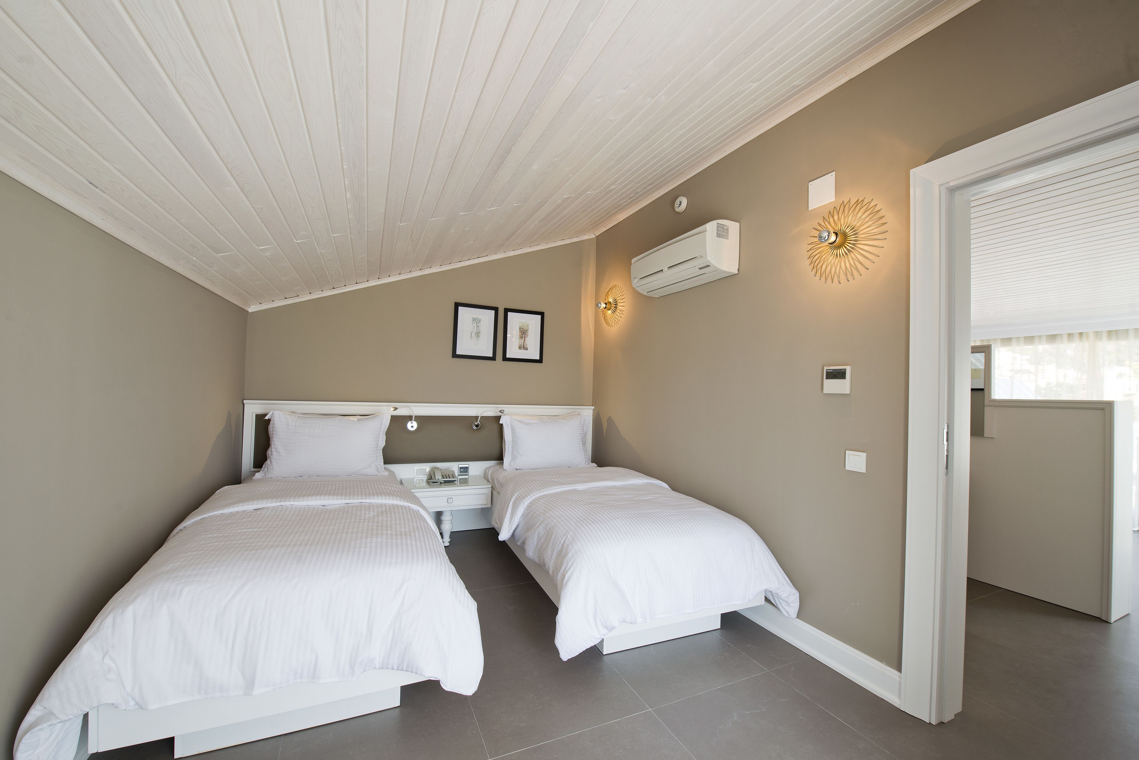 A bedroom with two beds, a ceiling fan, an air conditioning unit, and a wall-mounted light fixture.