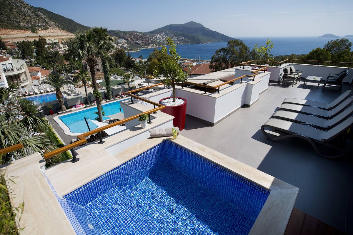 A rooftop pool area with a view of the sea and mountains.