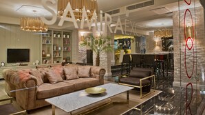 A modern hotel lobby with a plush sofa, a marble coffee table, and a dining area with a bar. - Samira Exclusive Hotel & Apartments (Kas)