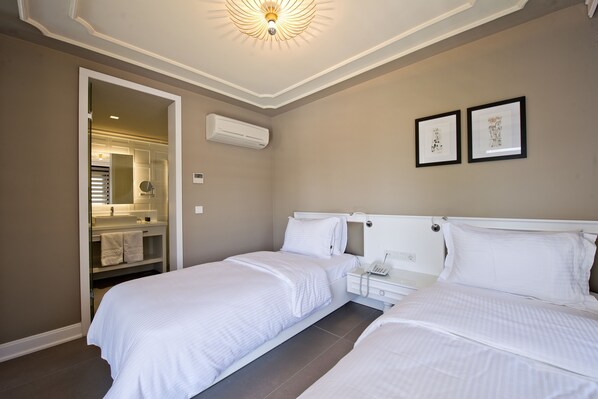 A hotel room with two beds, a bathroom with a mirror, and two framed pictures on the wall. - Samira Exclusive Hotel & Apartments (Kas)