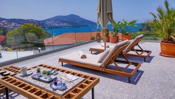 A rooftop terrace with lounge chairs, a table with a drink and snacks, and potted plants. - Samira Exclusive Hotel & Apartments (Kas)
