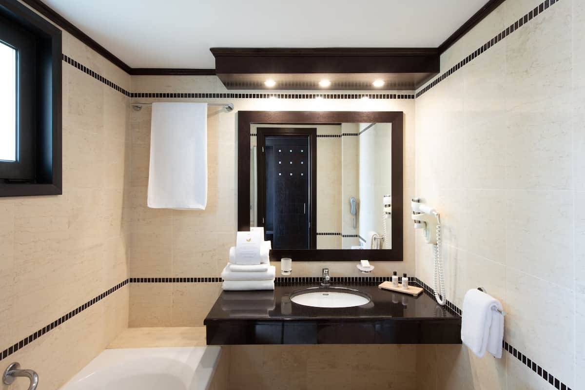 A modern bathroom with a bathtub, a sink, a mirror, and a towel rack.